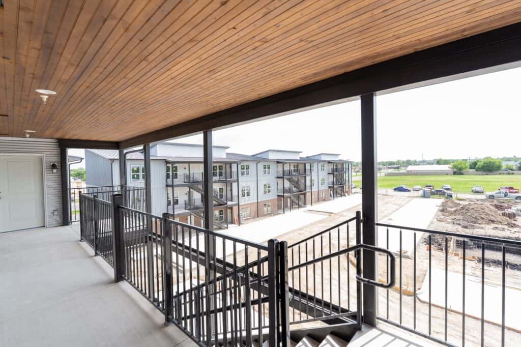 Balcony of The Exchange Apartments with black metal railing and scenic outdoor views.
